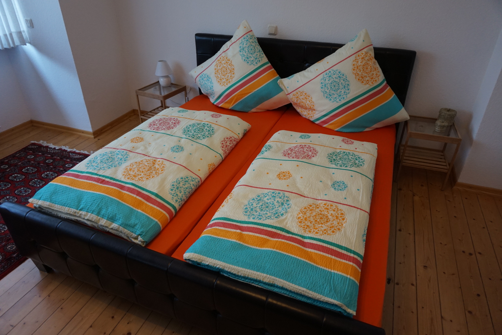 Schlafzimmer mit Doppelbett, bunten Bettbezügen und Nachttischen